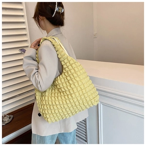 Shoulder view of a yellow pleated cloud tote bag made of high-quality canvas fabric
