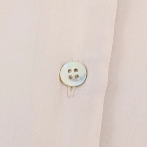 Macro shot of white four-hole buttons and fine stitching on a satin shirt