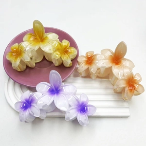 Three gradient 11.5cm flower hair claws in yellow, purple, and orange on a pink tray