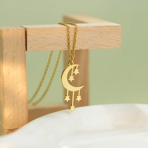 Golden moon and star pendant necklace with delicate O-chain on elegant wooden stand