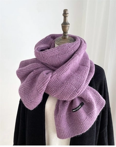 Detail of purple chunky knit checkerboard scarf with brand label on a mannequin