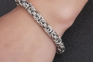 Macro view of men's Byzantine woven stainless steel chain bracelet with a polished finish