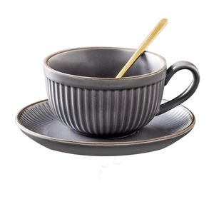 Detail of matte grey ceramic coffee cup with vertical stripe texture and golden spoon