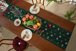 Close-up of woven Christmas table runner with Santa and gift motifs on a wooden table