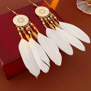 Détail de boucles d'oreilles attrape-rêves avec plumes blanches et perles dorées sur bois