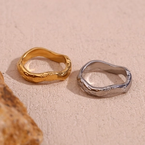 Detailed view of hammered gold and silver rings on natural rock against a textured surface