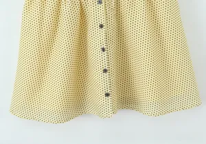 Macro detail of French V-neck dress with black polka dots and vertical dark buttons