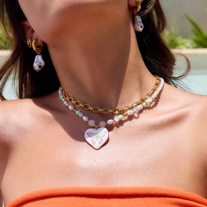 Détail du collier doré multicouche avec pendentif cœur papillon et boucles d'oreilles