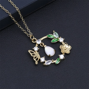 Gros plan du pendentif doré avec motifs de papillon, fleurs et pierres blanches serties