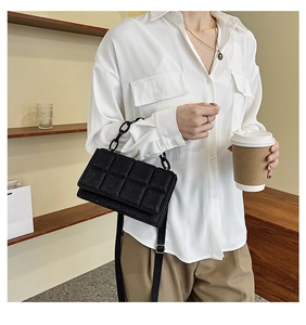 Detail of black glitter crossbody bag with quilted pattern and resin chain handle