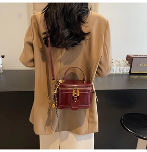Close-up of deep wine red box bag with polished leather texture and gold metal clasp