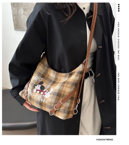Detail of plaid crossbody bag with dog illustration and brown leather piping trim