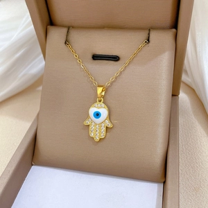 Detail of gold Hamsa Hand necklace with blue evil eye heart and sparkling zircon inlay
