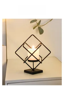 Detail of black geometric metal candle holder with a white pillar candle on wood desk