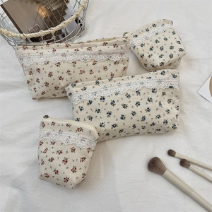 Detailed set of floral canvas cosmetic bags with lace trim and zippers on white fabric