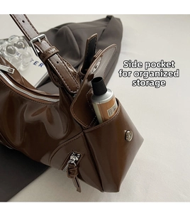 Detail of a brown leather shoulder bag featuring a side pocket with a metal magnetic buckle