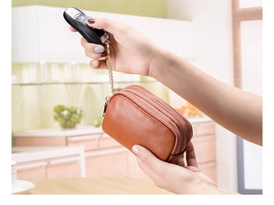Detail of genuine brown leather coin purse with triple gold zippers and keychain link