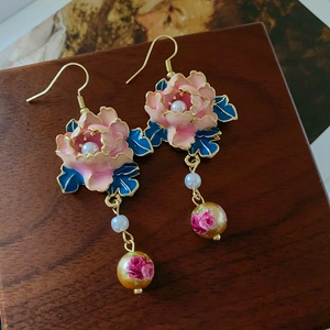 Detailansicht der Vintage-Ohrringe mit rosa Emaille-Blumen und Perlenquasten auf Holz