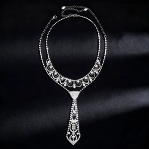 Détail du collier argenté en forme de cravate avec strass et perles sur fond noir