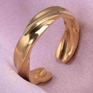 Macro shot of twisted irregular gold stainless steel ring on soft pink fabric