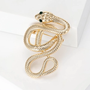 Detailed macro view of gold snake brooch with green gem eyes and scale textures