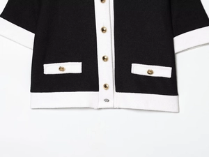 Détail de veste en maille bouclée avec boutons dorés et bordures blanches contrastantes