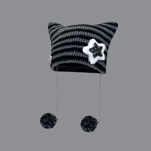Close-up of black and grey striped cat ear beanie with star patch and fuzzy pom-poms
