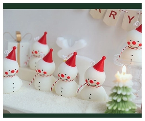 Détail d'une bougie parfumée bonhomme de neige festive avec chapeau rouge et sapin vert