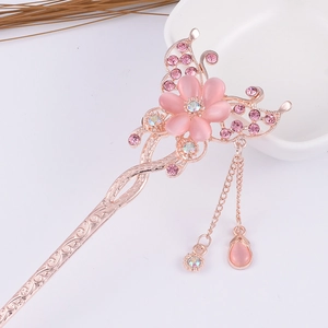 Detailed close-up of golden floral hair pin with pink petals, tassels and rhinestones