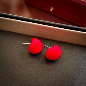 Close-up of red velvet teardrop earrings with a soft flocked texture and silver pins