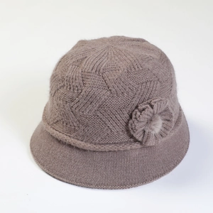 Detail of tan knitted cloche hat featuring decorative knit flower and faux fur center