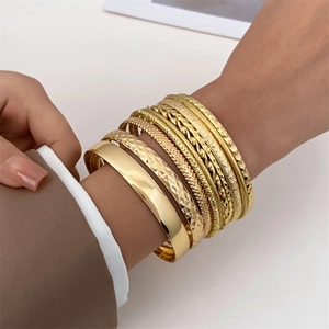 Detailed view of women's gold-plated stacked bangles with various textures and finishes
