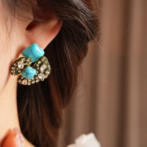 Detail of vintage turquoise and rhinestone earrings with irregular green metal design