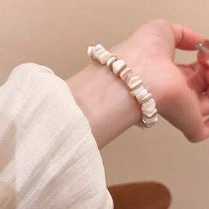 Detailed close-up of shell bead bracelet showing natural textures and creamy beige tones
