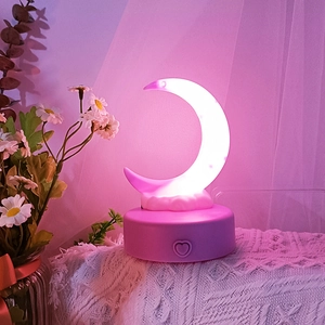 Detail view of pink moon and cloud night light with warm white glow on lace fabric