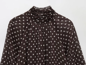 Detailed close-up of brown polka dot chiffon blouse featuring pleated high collar design