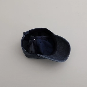 Detail of the blue washed denim baseball cap showing internal seams and metal buckle