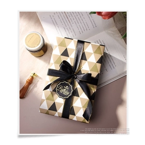 Gift box wrapped in black and gold geometric paper with a black ribbon and birthday tag