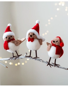 Three plush Christmas birds wearing red hats and scarves on frost-covered twigs