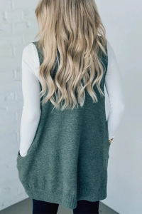 Back view of dark green knit vest with a long-line fit over a white long-sleeve shirt