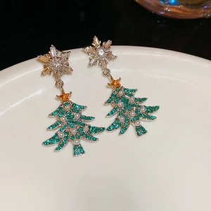Close-up of snowflake and green Christmas tree earrings with pearls and crystal inlay