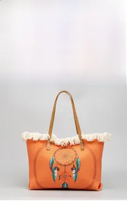 Close-up of woven orange canvas tote bag with dreamcatcher print and cream fringes