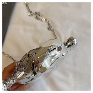 Macro detail of silver candy-shaped acrylic bag with pleated metallic texture and chain