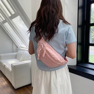 Detail view of pink nylon chest bag with woven zipper pull and crossbody strap design
