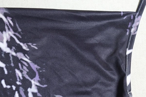 Detail of purple snake print on black bodycon dress showing fabric texture and thin strap