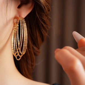 Close-up of golden multi-layered textured hoop earrings worn by a female model