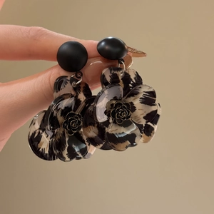 Detail of leopard print flower earrings with golden rose center and matte black studs
