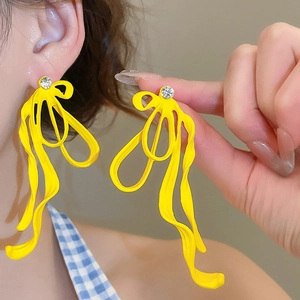 Macro shot of vibrant yellow ribbon bow earrings with a sparkling zircon crystal stud