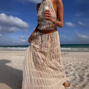 Detail of bohemian cream halter top and tiered pleated maxi skirt on beach