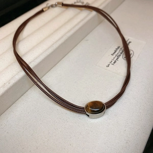 Detailed close-up of brown braided choker necklace with oval tiger eye stone pendant